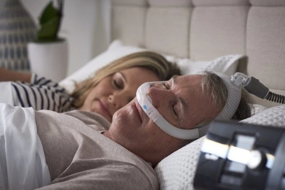 Man with CPAP machine and sleeping partner