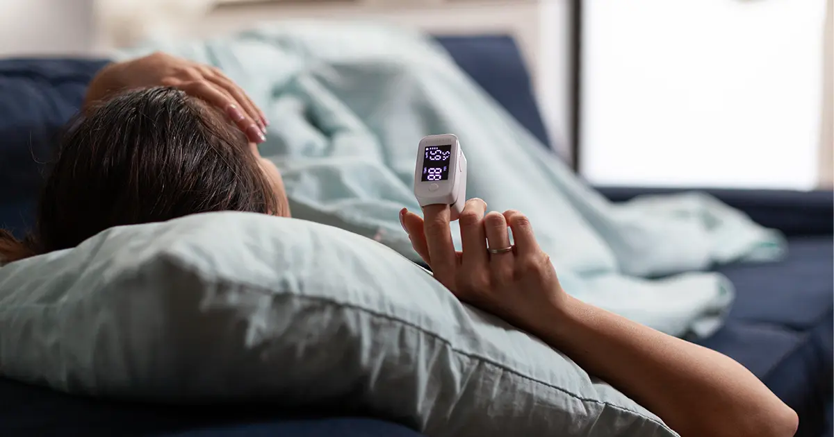 Person in bed with cardiac finger monitor